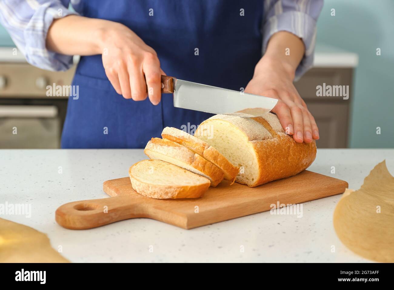 Chef femminile che taglia pane fresco sul tavolo da cucina