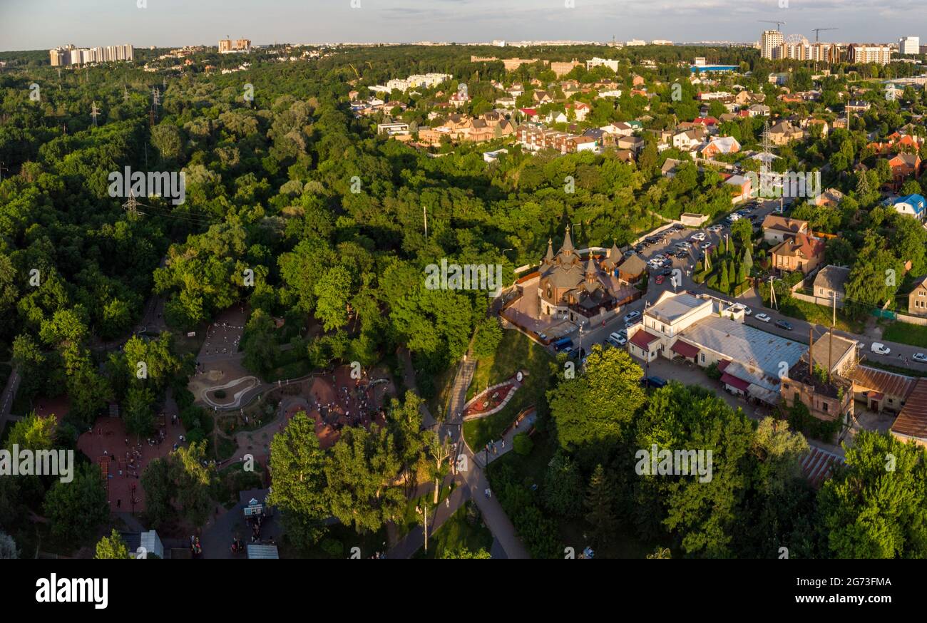 Vista aerea sera sul parco giochi e la chiesa in estate verde Kharkiv centro città popolare parco ricreativo Sarzhyn Yar. Giardino Botanico in residenziale Foto Stock