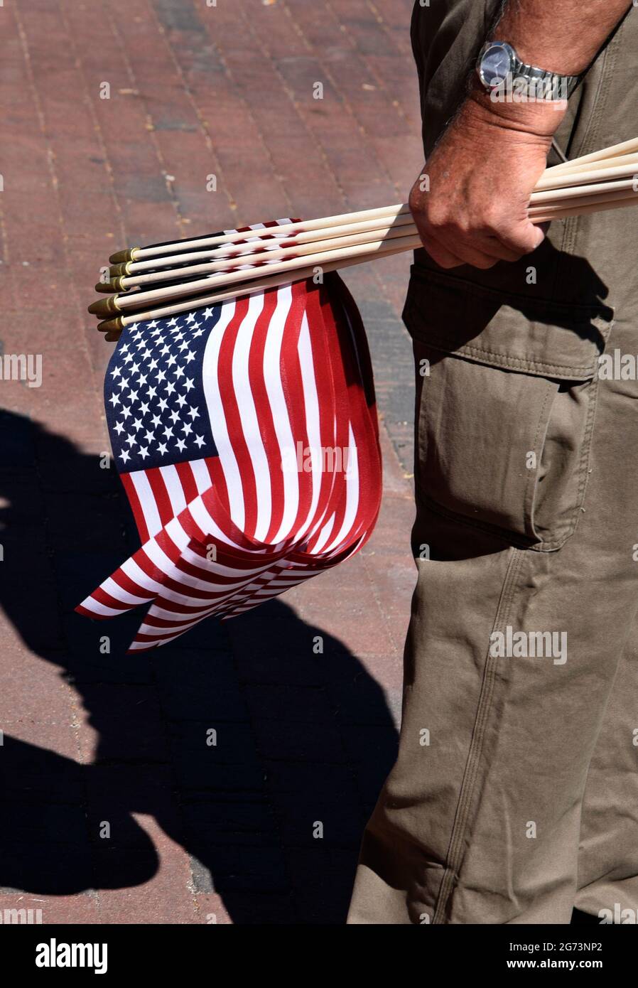 Un uomo distribuisce piccole bandiere americane in una mostra di auto classiche del 4 luglio a Santa Fe, New Mexico. Foto Stock