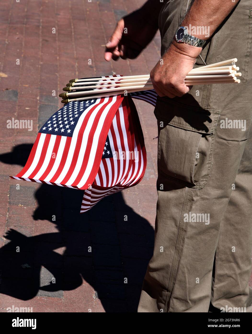 Un uomo distribuisce piccole bandiere americane in una mostra di auto classiche del 4 luglio a Santa Fe, New Mexico. Foto Stock