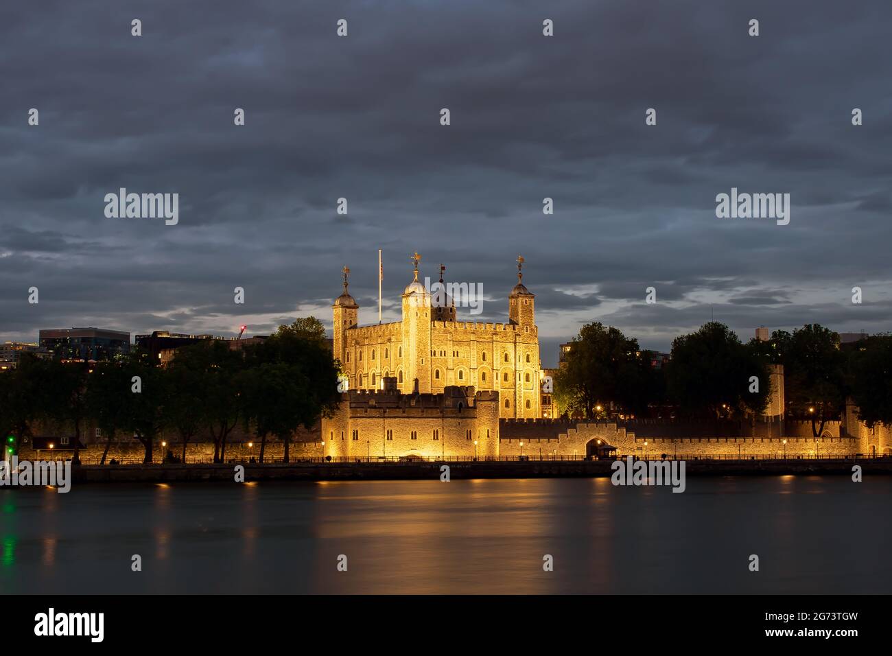 La Torre di Londra è illuminata di notte, come si vede dalle rive meridionali del Tamigi a Londra, Inghilterra. Le luci si riflettono sull'acqua. Foto Stock