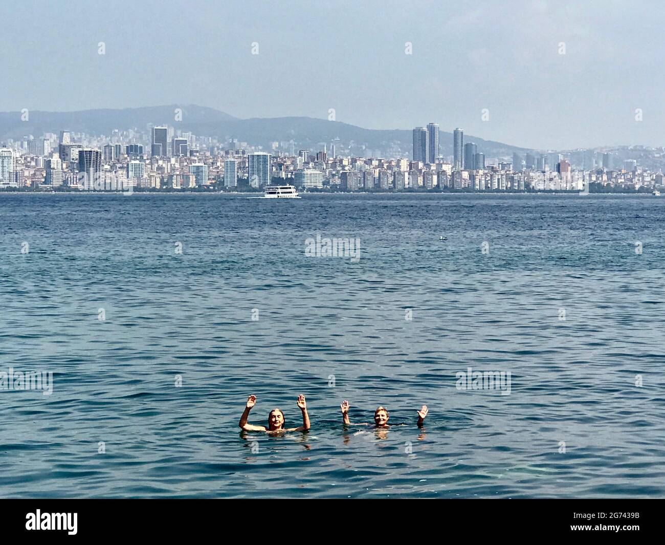 Persone che nuotano nel Mar Bosforo vicino alle Isole Principesse con lo skyline di Istanbul, Turchia sullo sfondo. Foto Stock