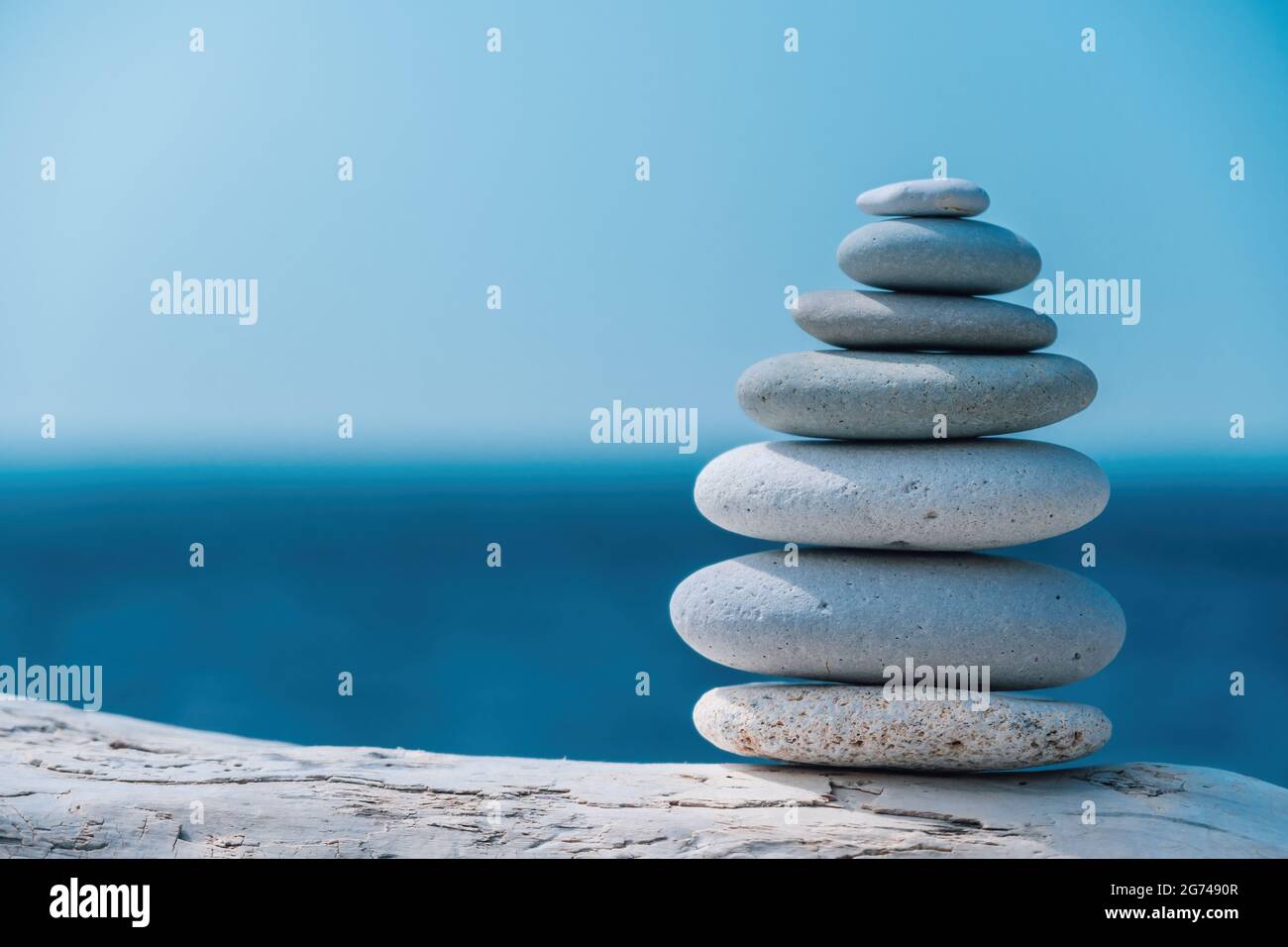 Equilibrata piramide di ciottoli sulla spiaggia in una giornata di sole. Abstract Sea bokeh sullo sfondo. Messa a fuoco selettiva. Pietre Zen sulla spiaggia di mare, meditazione Foto Stock
