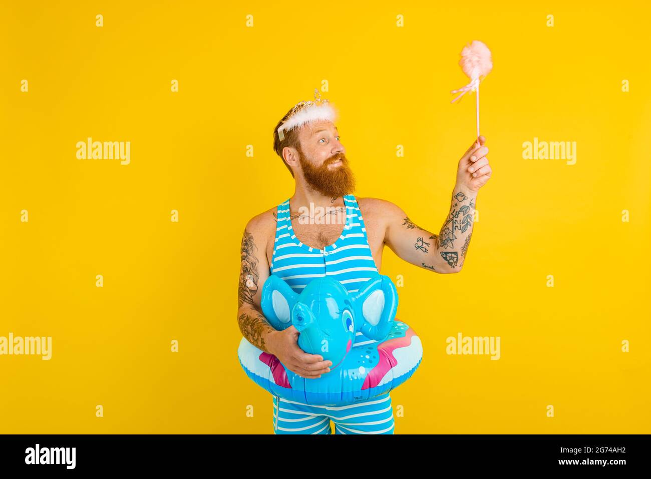 Uomo felice con buoy di vita, corona principessa e bacchetta magica agisce come una fata Foto Stock