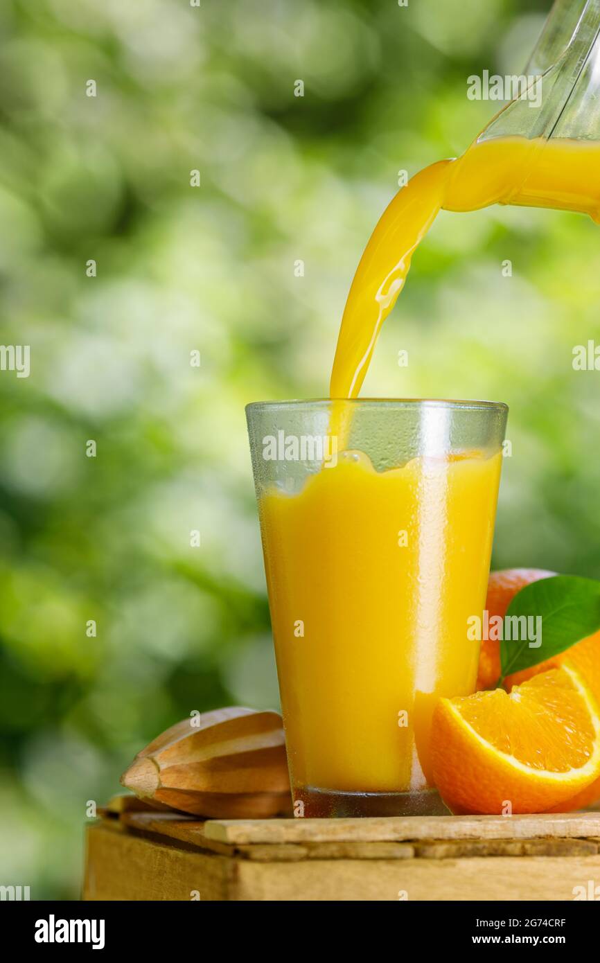 succo d'arancia freddo appena spremuto che viene versato in un bicchiere Foto Stock