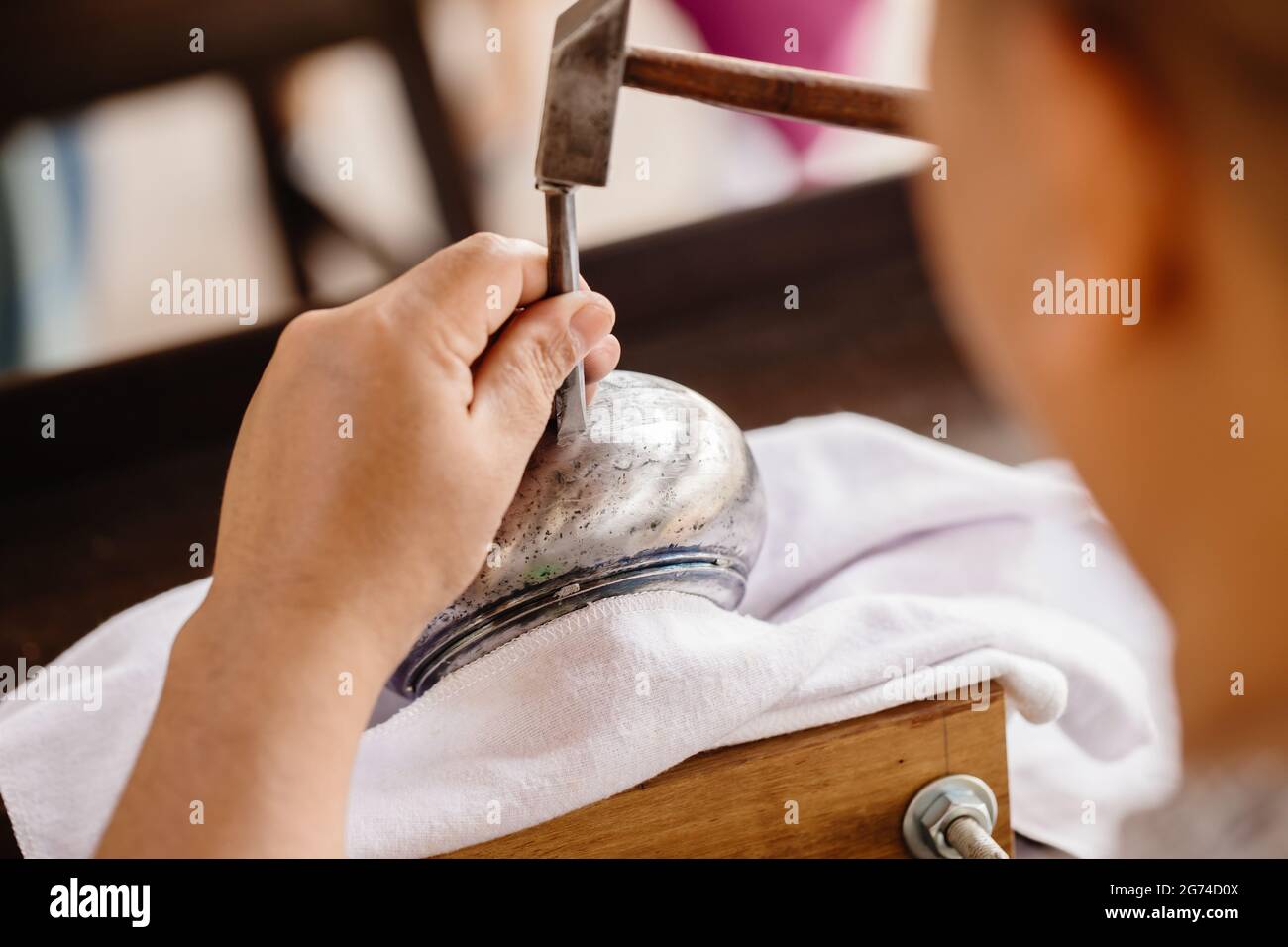 Closeup martello da lavoro artigianale professionale maschile inciso sul capolavoro di arte asiatica artigianale della ciotola in argento. Foto Stock