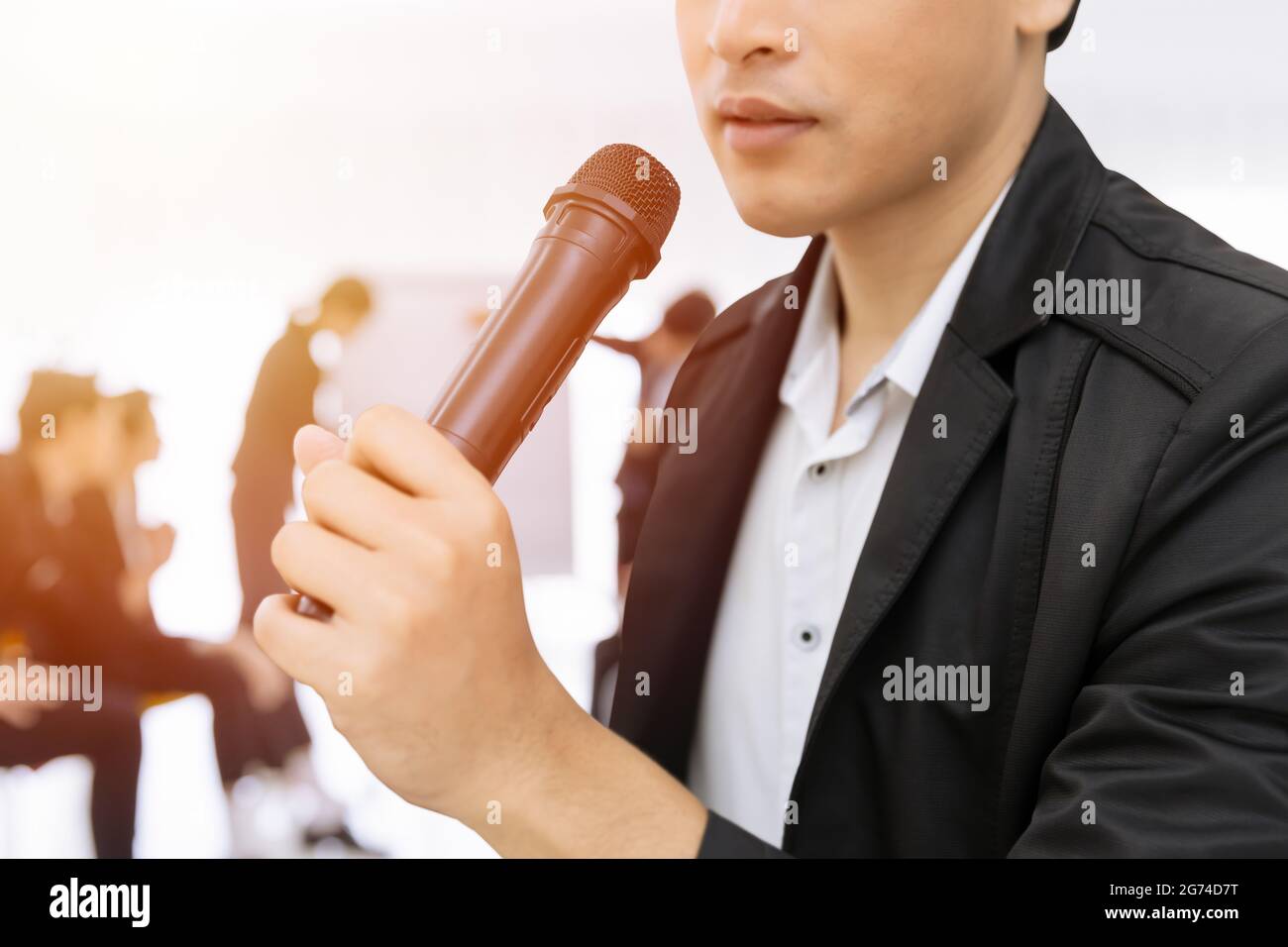 Closeup Male Hand Holding microfono che parla nel seminario di affari. Speaker uomo lezione riunione o concetto di talk show. Foto Stock