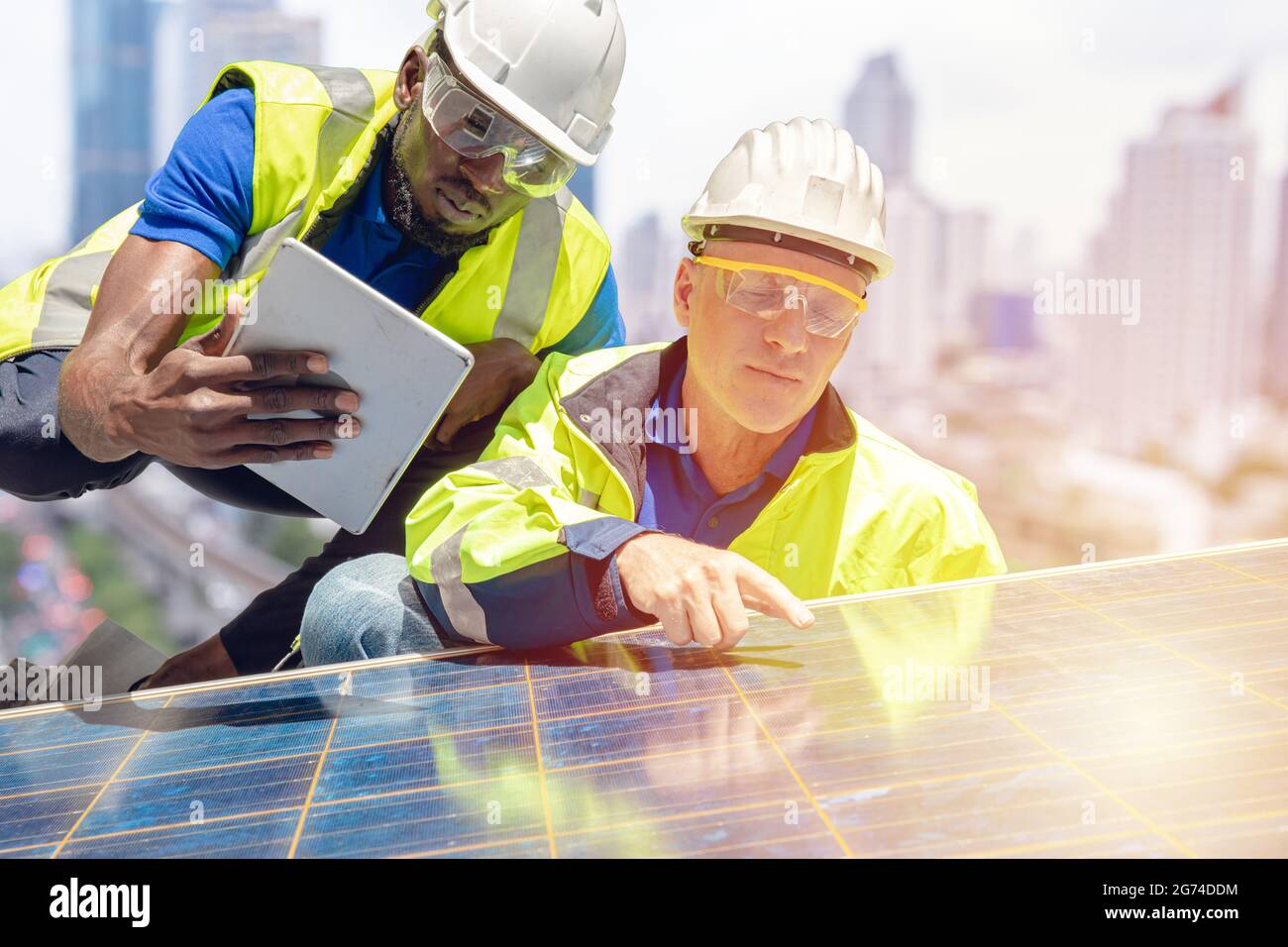 Gruppo di ingegneri che lavora su pannello solare sul tetto dell'edificio aziendale. Il lavoro di squadra lavora insieme per installare il sistema di celle fotovoltaiche di manutenzione. Foto Stock