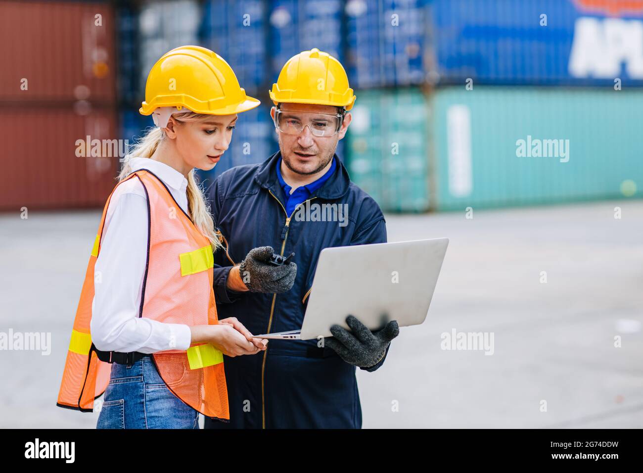 Il team dei lavoratori logistici che lavorano nel trasporto di container portuali per l'esportazione e il monitoraggio delle merci d'importazione con computer portatile. Foto Stock