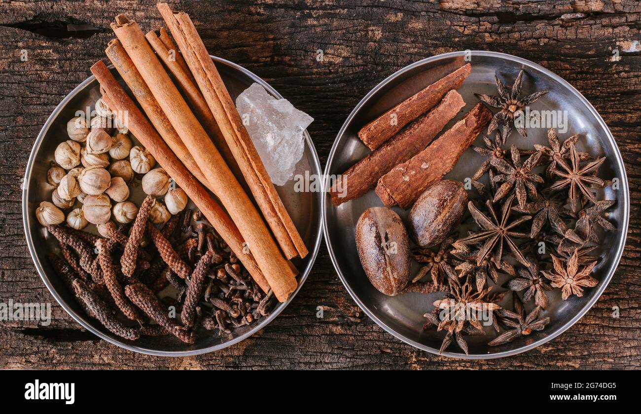 Mix di erbe secche asiatiche indiane per la medicina alternativa o aromatherapy e l'ingrediente di aromatizzante alimentare posano topview su sfondo di legno. Foto Stock