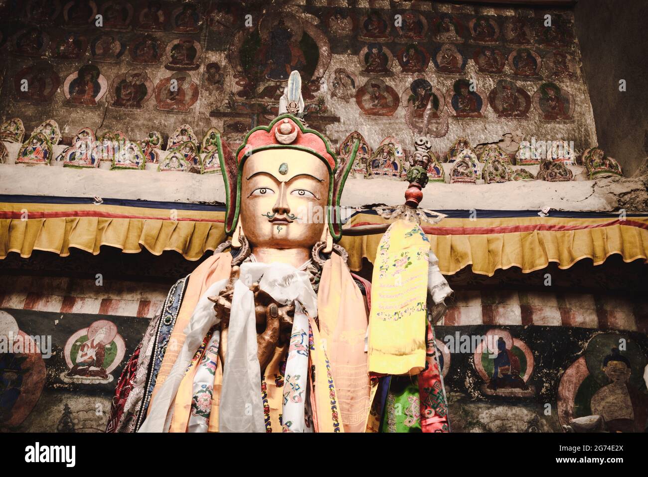 Statua dorata di padma sambawa, Padmasambhava in un monastero tibetano con vecchio religioso, pittura buddista sullo sfondo. India, Himachal Pradesh. Foto Stock