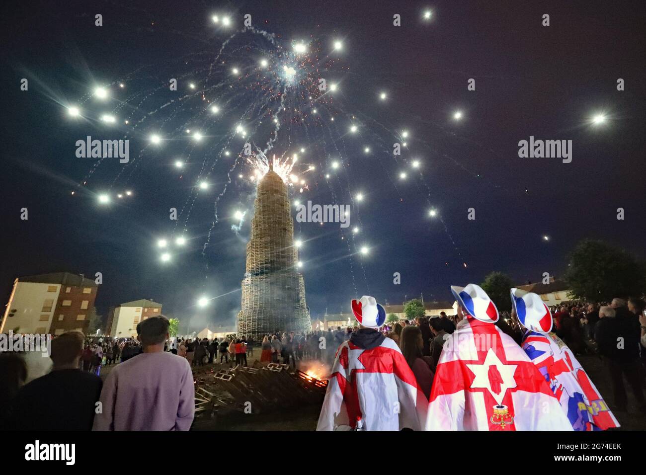 La folla guarda uno spettacolo di fuochi d'artificio prima che l'enorme falò nella zona lealista di Corcrain di Portadown, Co Armagh, si illumini l'"undicesima notte" per inaugurare le dodici commemorazioni. Data immagine: Sabato 10 luglio 2021. Foto Stock