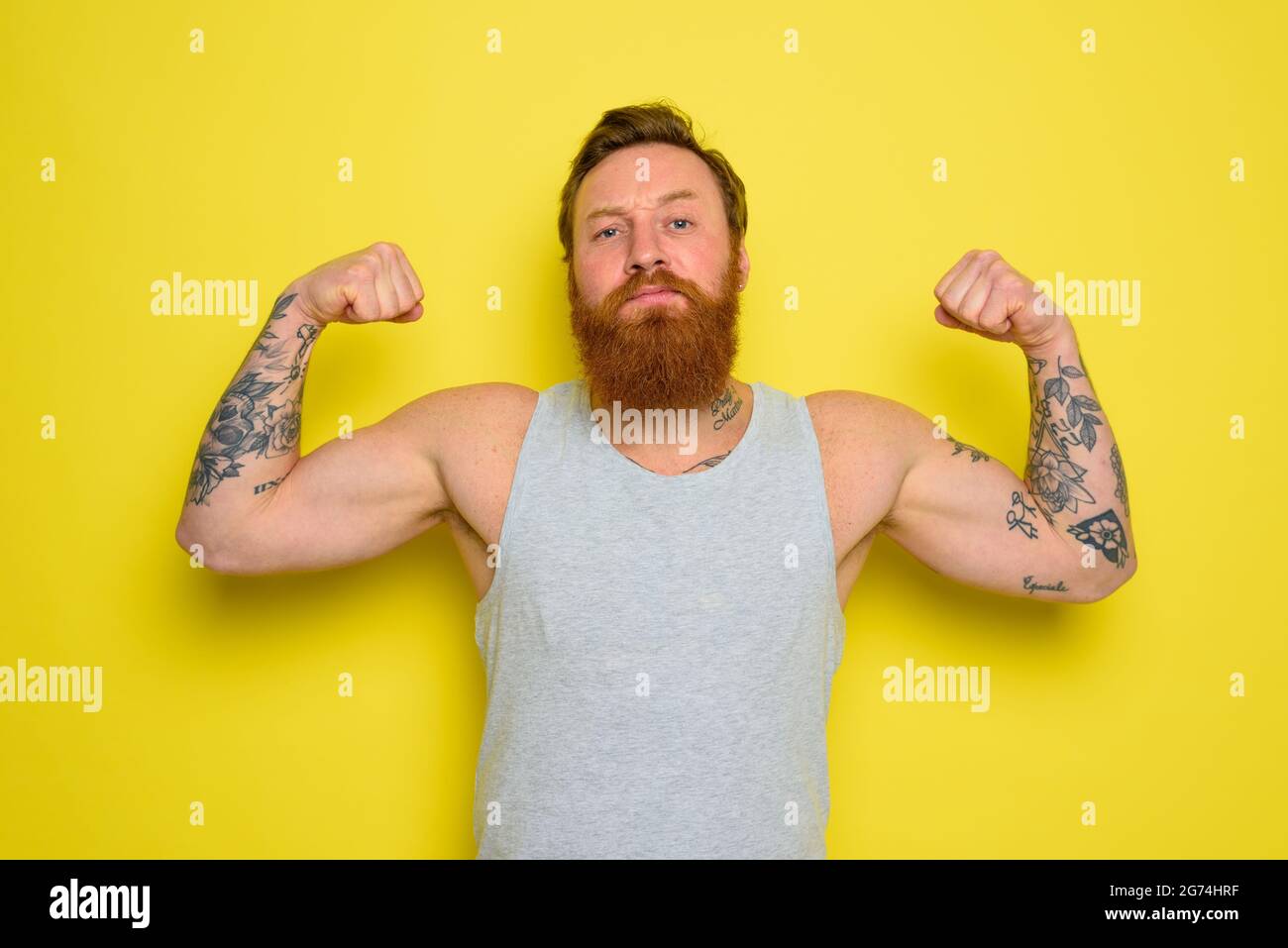 L'uomo con barba e tatuaggi mostra con orgoglio il suo muscolo Foto Stock