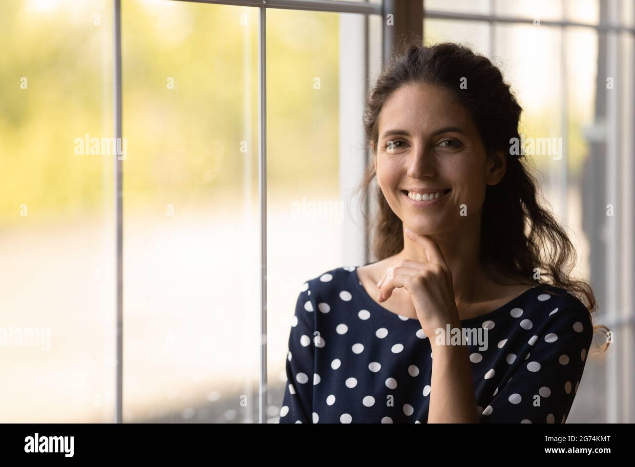Ritratto di felice millenario latino 30s donna che tocca il mento Foto Stock