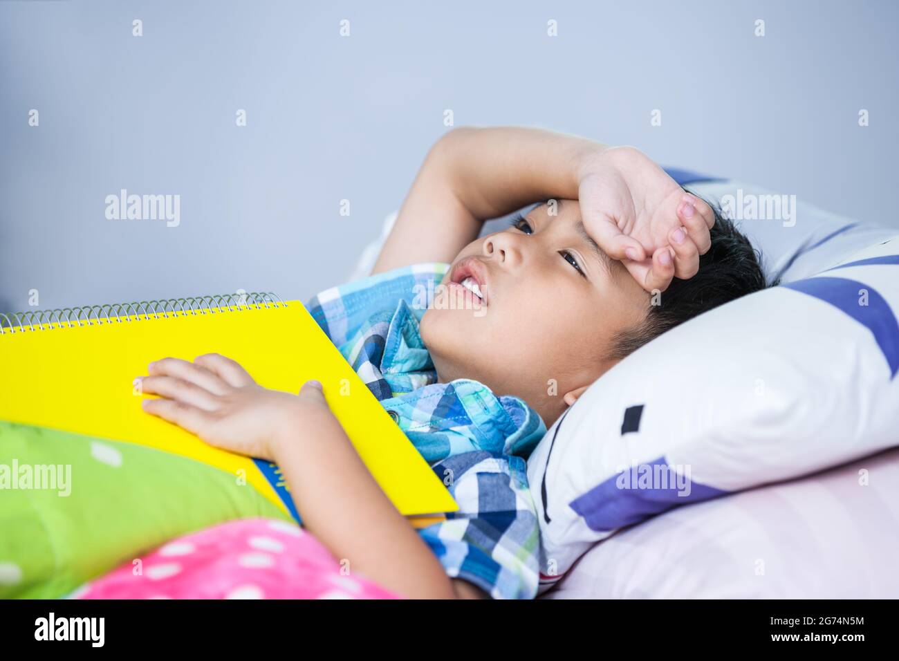 Stanco e annoiato bambino infelice quando ha letto un libro sul letto in camera da letto. I bambini leggono e studiano, studiano duro, studentesse stanche, concetto di educazione. Foto Stock