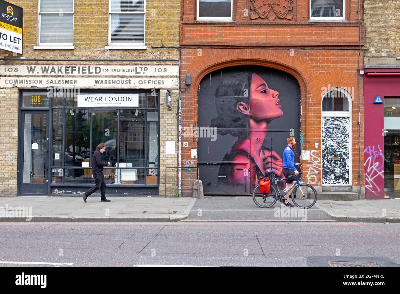 Persone che camminano oltre murale pittura illustrazione di donna rosa di artista David Speed in Spitalfields quartiere Shoreditch East London UK KATHY DEWITT Foto Stock