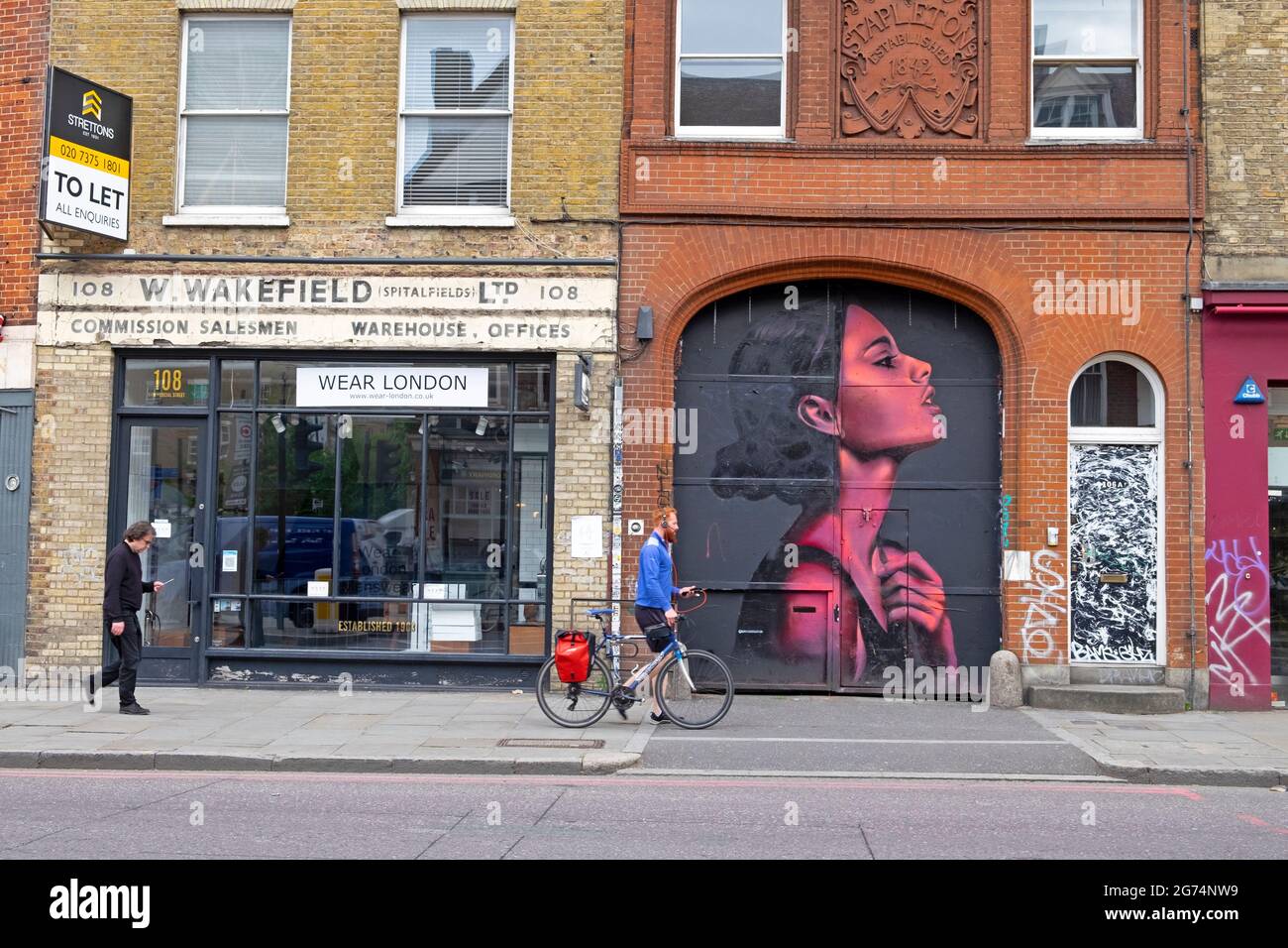 Persone che camminano oltre murale pittura illustrazione di donna rosa di artista David Speed in Spitalfields quartiere Shoreditch East London UK KATHY DEWITT Foto Stock