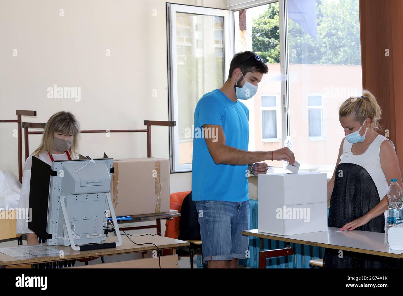 Le persone con maschere stanno usando una macchina di voto nelle elezioni parlamentari bulgare a Sofia, Bulgaria, il 11 luglio 2021 Foto Stock
