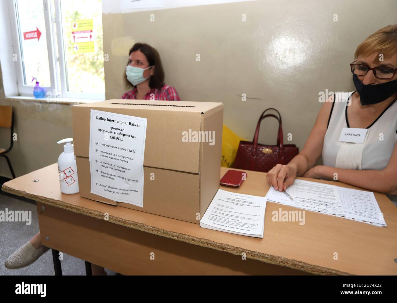 Le persone con maschere stanno usando una macchina di voto nelle elezioni parlamentari bulgare a Sofia, Bulgaria, il 11 luglio 2021 Foto Stock