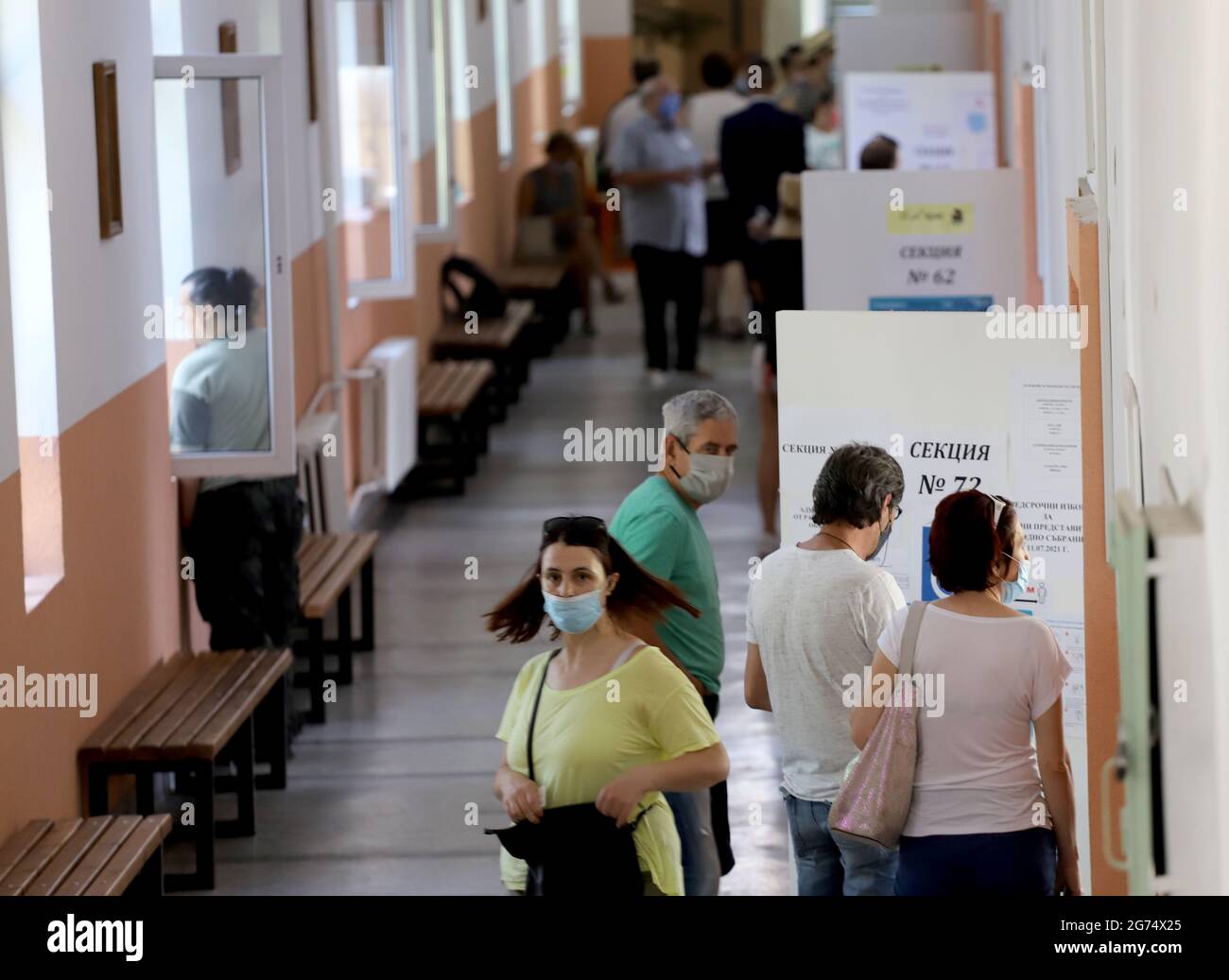 Le persone con maschere stanno usando una macchina di voto nelle elezioni parlamentari bulgare a Sofia, Bulgaria, il 11 luglio 2021 Foto Stock