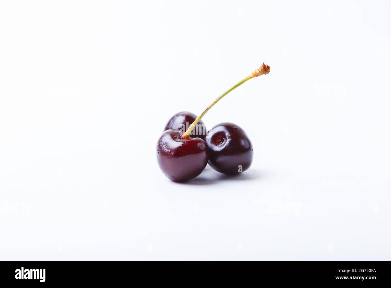 Tre ciliegi su sfondo bianco. Primo piano, spazio di copia per il testo. Foto Stock