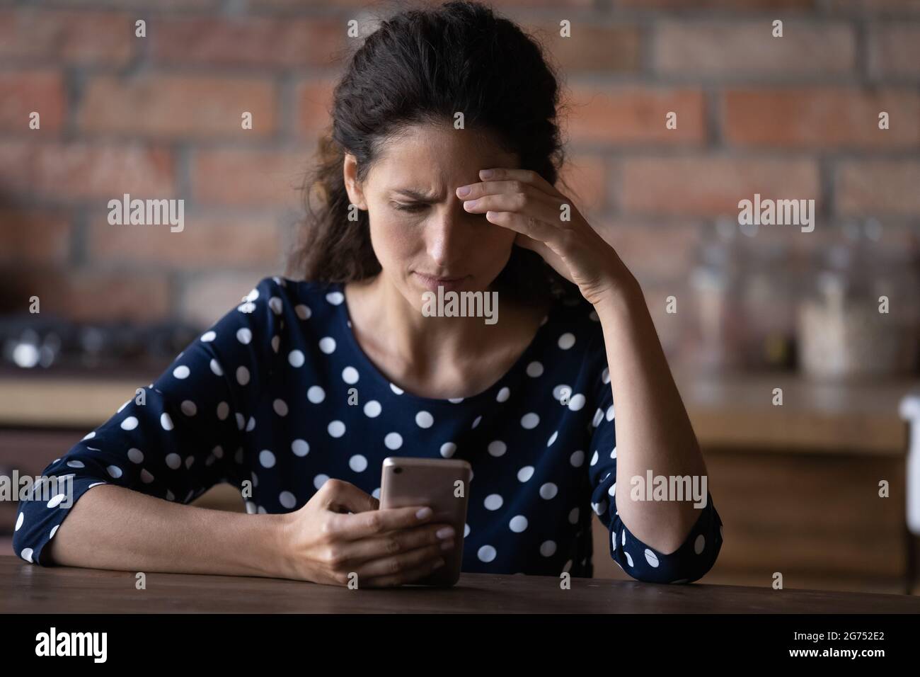 Preoccupata donna latina che ha problemi con il telefono cellulare Foto Stock