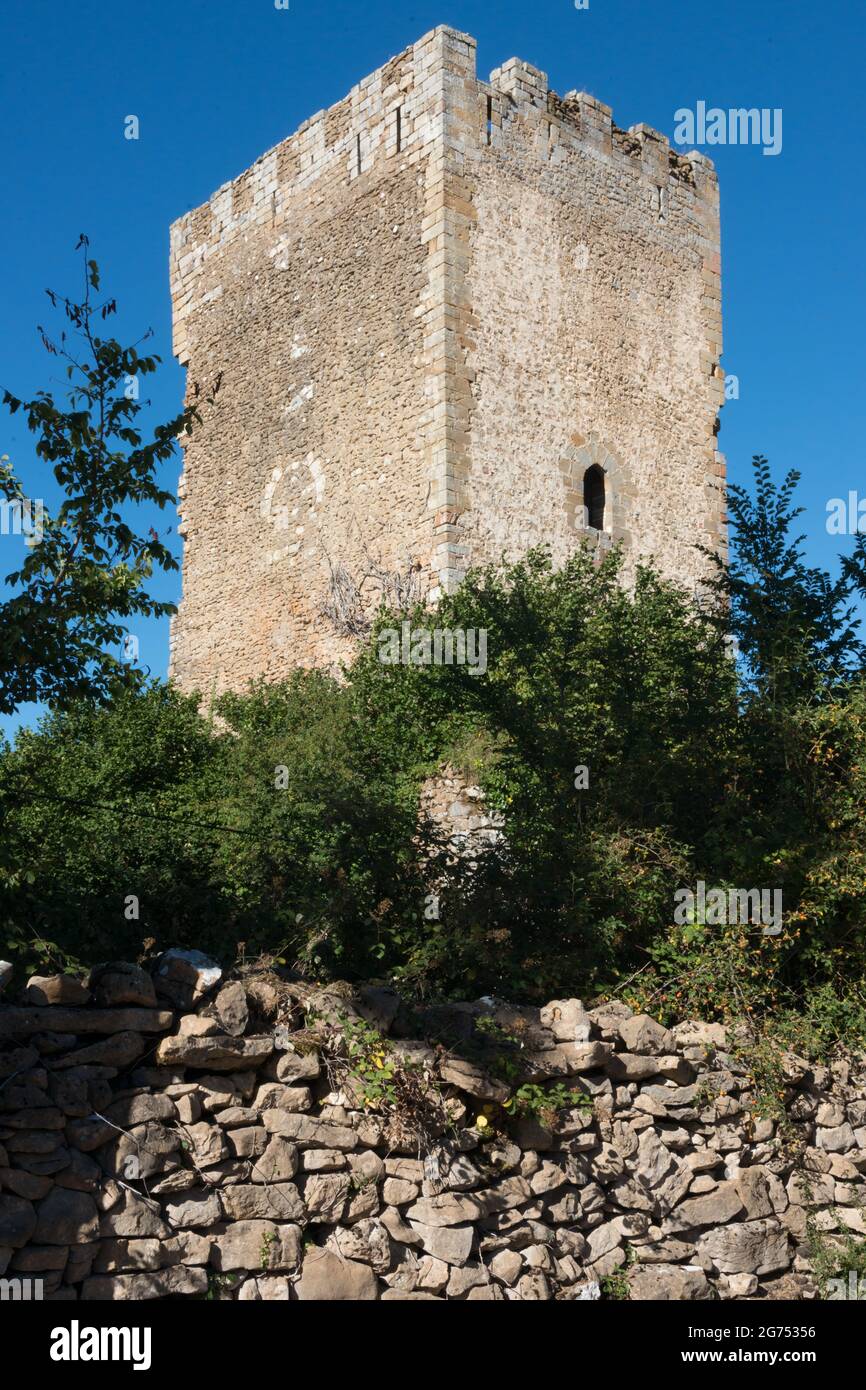 Antica torre in pietra con una piccola finestra. Cielo blu, nessuna gente, alberi intorno e muro circostante. Merindades, Burgos, Spagna, Europa Foto Stock