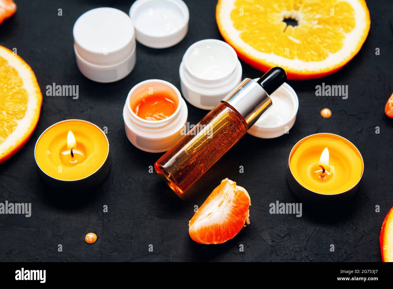 Vitamina C cura della pelle del viso concetto cosmetico - siero organico in una bottiglia e crema con ingredienti naturali. Fette tangerine e arancioni. Foto Stock