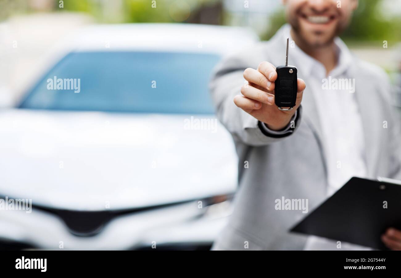 Auto business, vendita auto, affare, gesto e concetto di persone. Il concessionario dà la chiave al nuovo proprietario Foto Stock