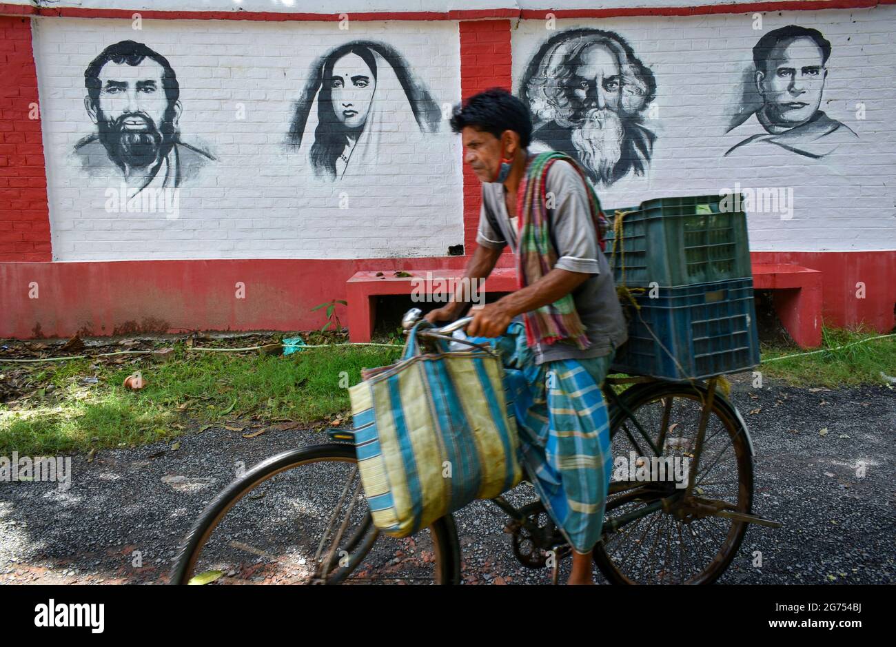 Kolkata, India. 11 Luglio 2021. Una persona che cavalca in bicicletta accanto ad un murale di personaggi famosi (da sinistra - Sri Ramakrishna, Sarada Devi, Rabindranath Tagore e Ishwar Chandra Vidyasagar) dell'India un abbaino a Kolkata. (Foto di Sudipta Das/Pacific Press) Credit: Pacific Press Media Production Corp./Alamy Live News Foto Stock