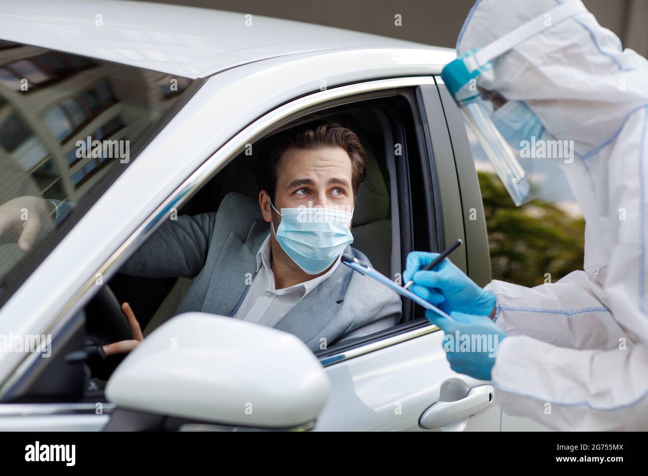 Controlla passeggeri e driver per virus, uomo in tuta biologica scrive dati su tablet, COVID-19 quarantena Foto Stock