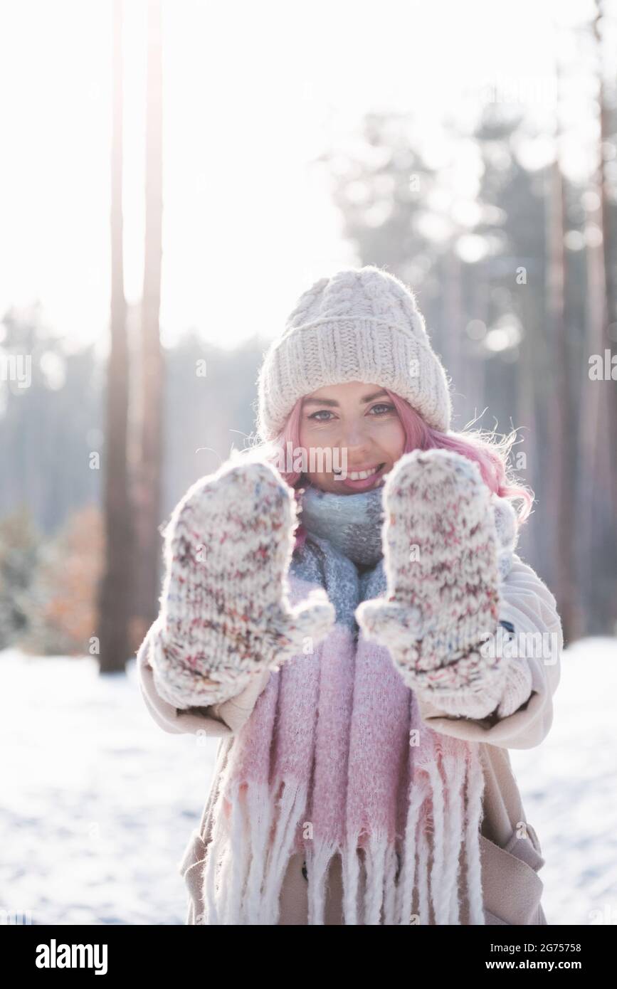 Donna d'inverno che guarda felice e sorridente all'aperto nella neve in freddo giorno d'inverno Foto Stock