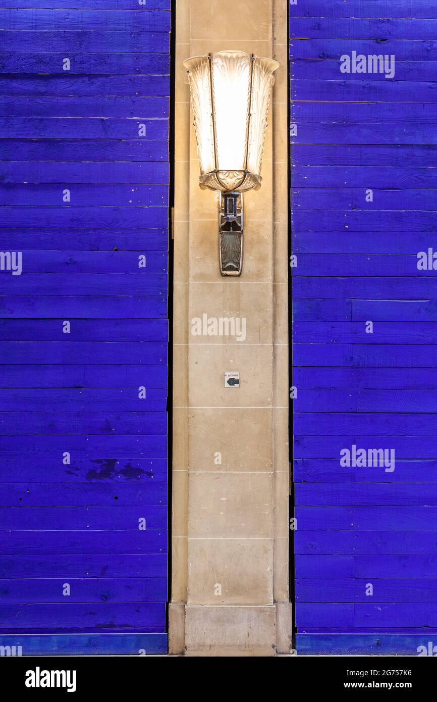 Lanterna illuminata fissata ad una colonna tra due sezioni di pareti blu intenso. Parigi, Francia Foto Stock