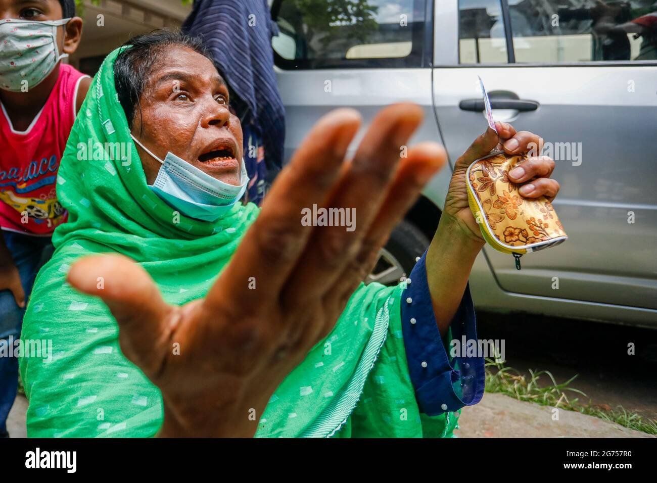 Una donna che tiene la foto della sorella al Dhaka Medical College Hospital come medici ufficiali raccogliere campioni di sangue dai parenti delle vittime o Foto Stock