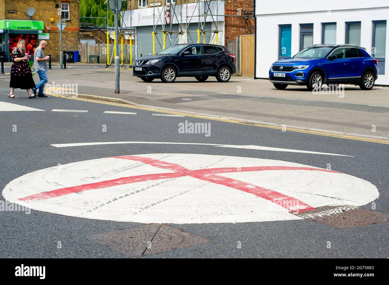 Dedworth, Windsor, Berkshire, Regno Unito. 11 Luglio 2021. Una serie di mini rotatorie a Dedworth, Windsor, sono state dipinte con una croce rossa per apparire come la bandiera di Inghilterra di San Giorgio prima della finale UEFA Euro 2020 stasera tra Inghilterra e Italia. Operai per il Royal Borough di Windsor e Maidenhead sono venuti e dipinte sopra le croci rosse ma sono riapparsi di nuovo. Credit: Maureen McLean/Alamy Live News Foto Stock