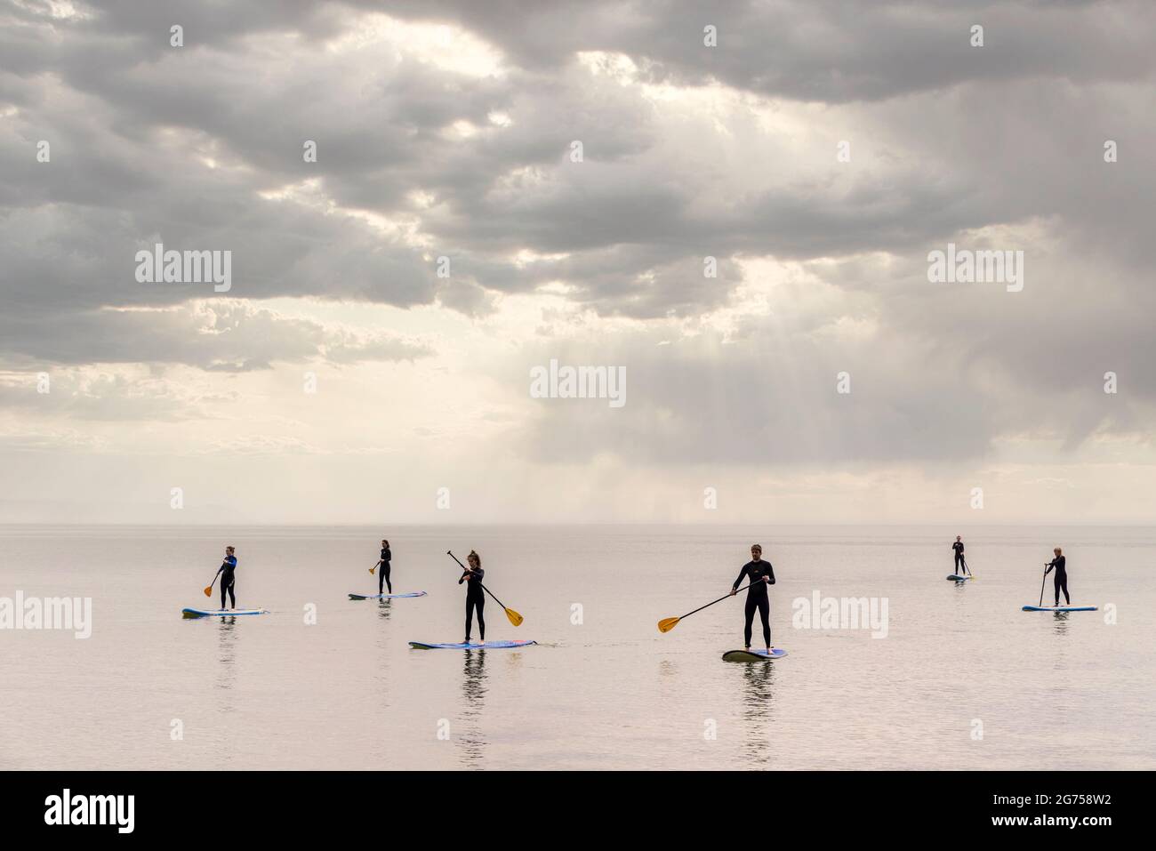 Paddle boarders sul mare calmo a Barafundle Bay, Pembrokeshire, Galles, Regno Unito Foto Stock