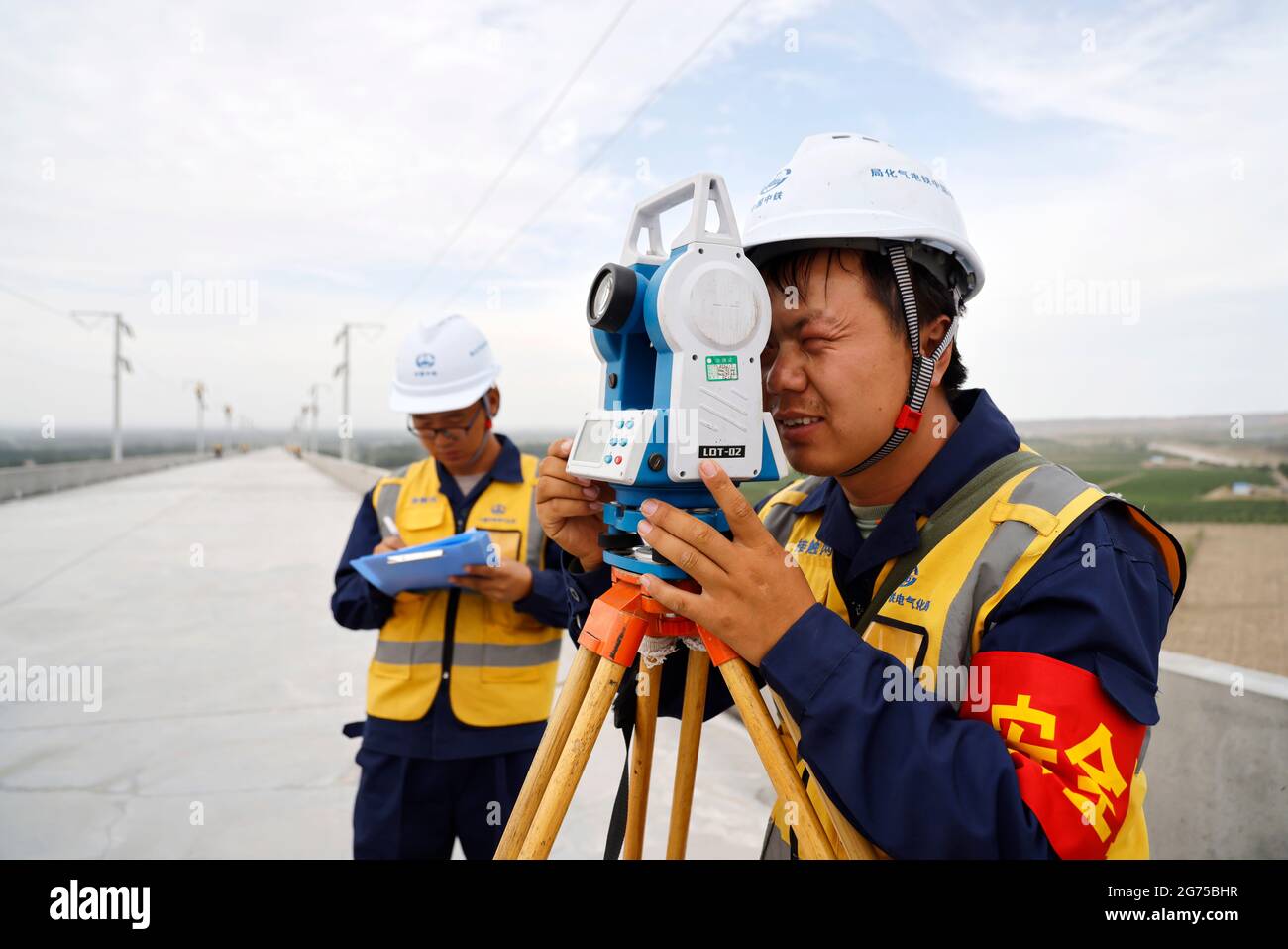(210711) -- YINCHUAN, 11 luglio 2021 (Xinhua) -- i membri del personale ferroviario lavorano nella sezione Zhongwei della linea ferroviaria ad alta velocità Zhongwei-Lanzhou, nella regione autonoma di Ningxia Hui nella Cina nord-occidentale, 10 luglio 2021. Una delle principali ferrovie ad alta velocità della Cina nordoccidentale è entrata recentemente in una fase chiave, in cui è stata implementata la costruzione di un sistema di contatto aereo. La ferrovia, che collega Zhongwei e Lanzhou, capitale della vicina provincia di Gansu, è prevista per misurare 218.5 chilometri con una velocità massima di 250 km all'ora. La linea, che dovrebbe aprirsi nel 2022, si collegherà con anot Foto Stock