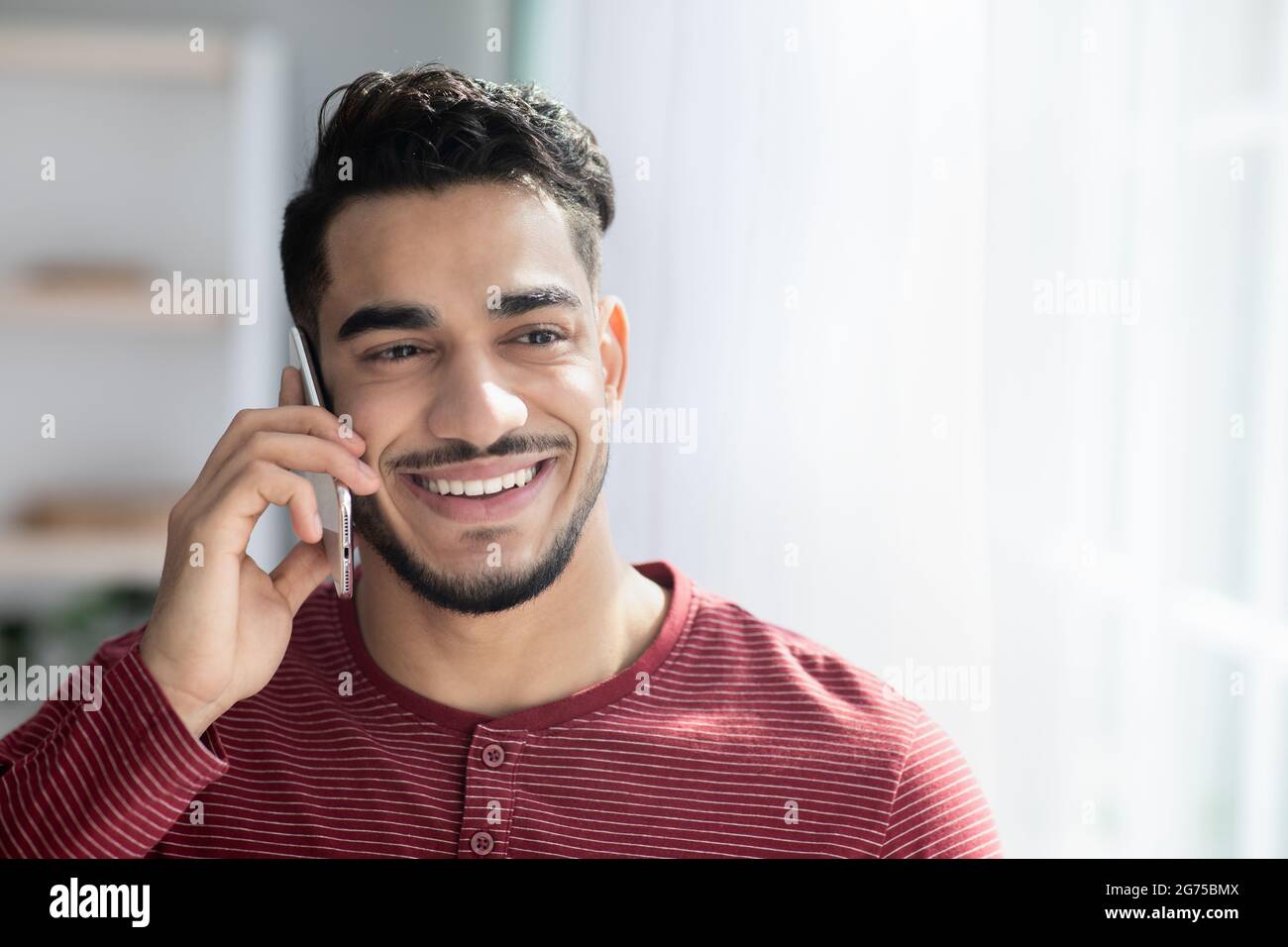 Felice ragazzo medio-orientale che parla sul telefono cellulare Foto Stock