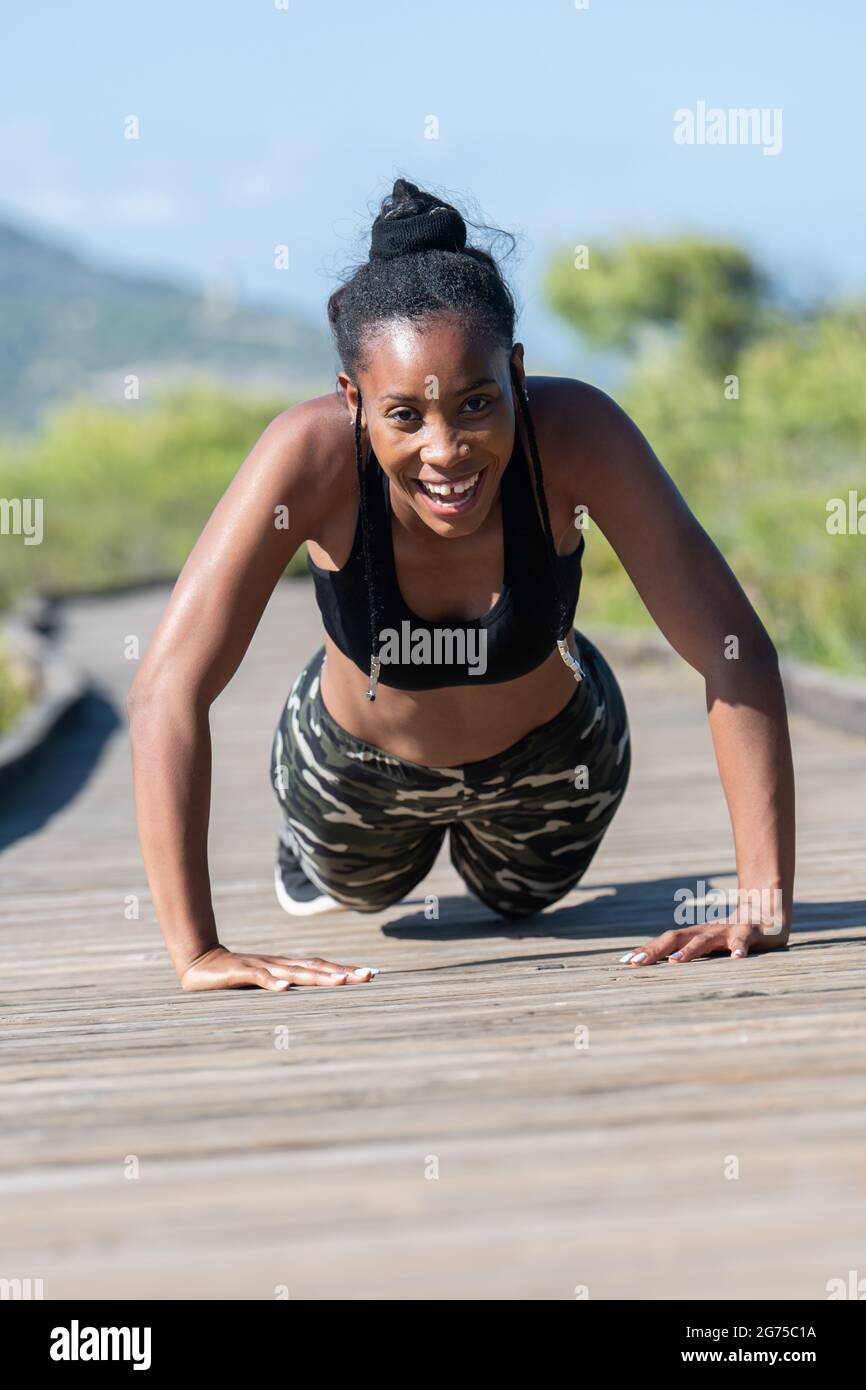 Lotta afro donna americana facendo spingere su una pista di legno: Esercizio e sforzo concetto. Foto Stock