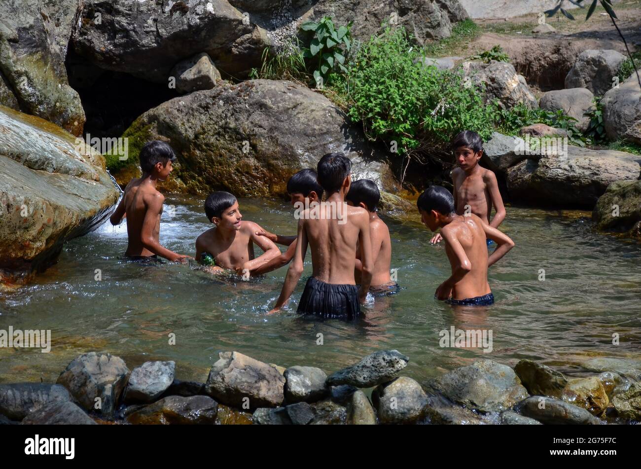 Srinagar, India. 11 Luglio 2021. I bambini del Kashmiri si rinfrescano in un ruscello durante una calda giornata estiva alla periferia di Srinagar. (Foto di Saqib Majeed/SOPA Images/Sipa USA) Credit: Sipa USA/Alamy Live News Foto Stock