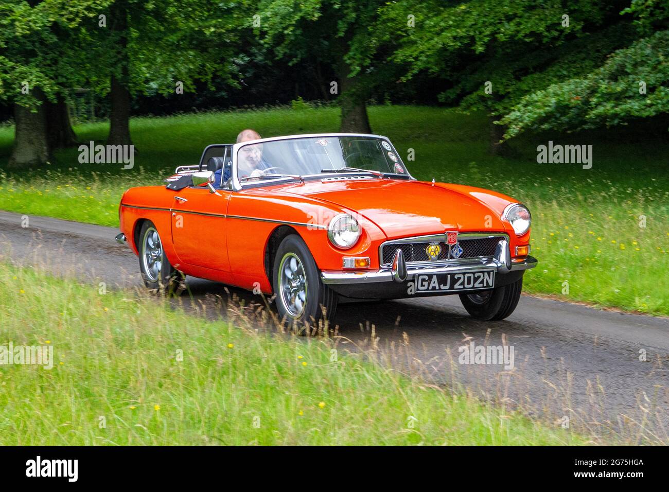 Una vista frontale di arancio 1974 70s MG B (MGB) arancione 2dr 1798cc Roadster; vintage classica auto sportiva retro British driver car, UK Foto Stock