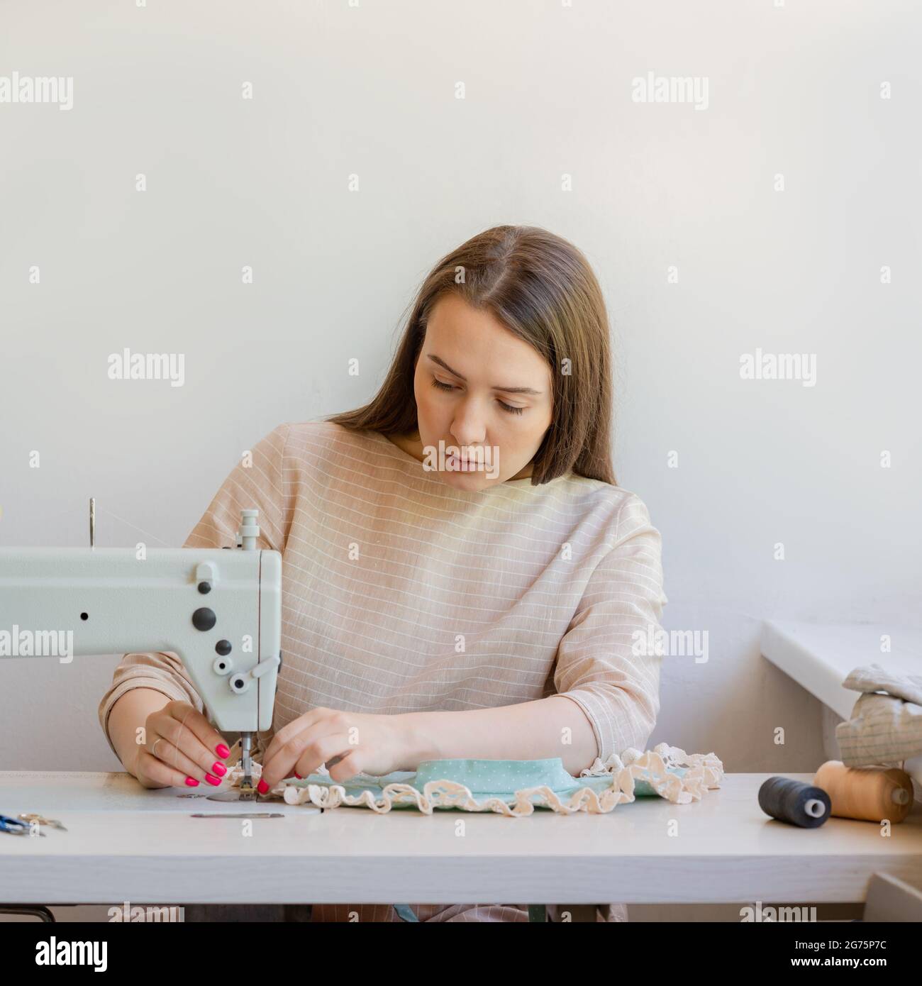 Vestiti da cucire concentrati di Seamstress al suo atelier di moda Foto Stock