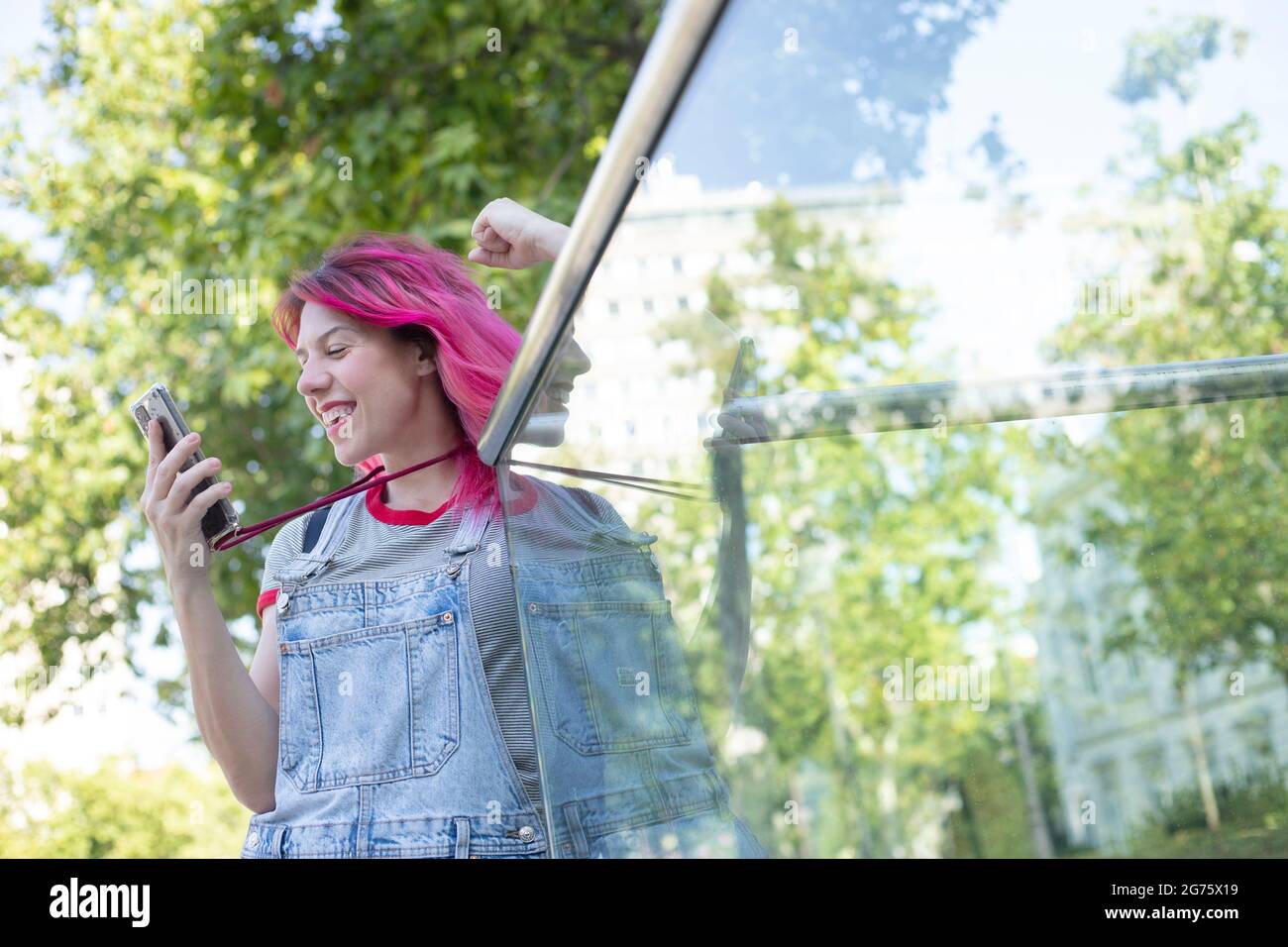 donna con capelli rosa all'aperto guardando il suo schermo del telefono cellulare Foto Stock