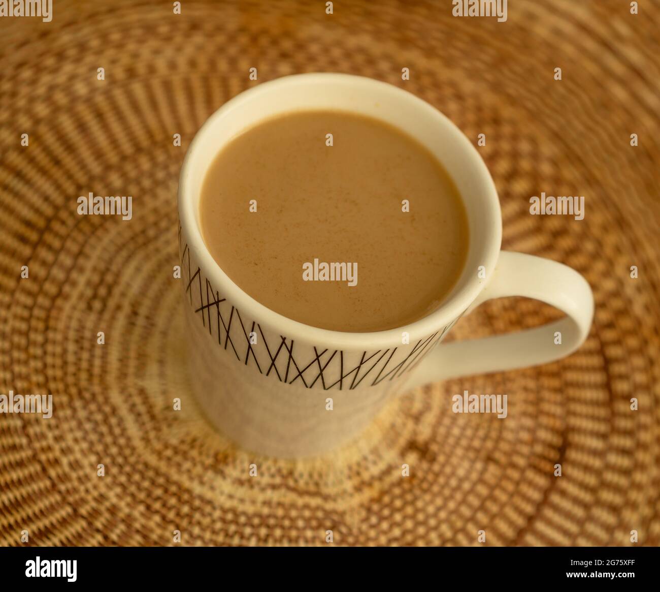Caffè con latte e cannella in tazza su una tovaglia di tessuto marrone Foto Stock