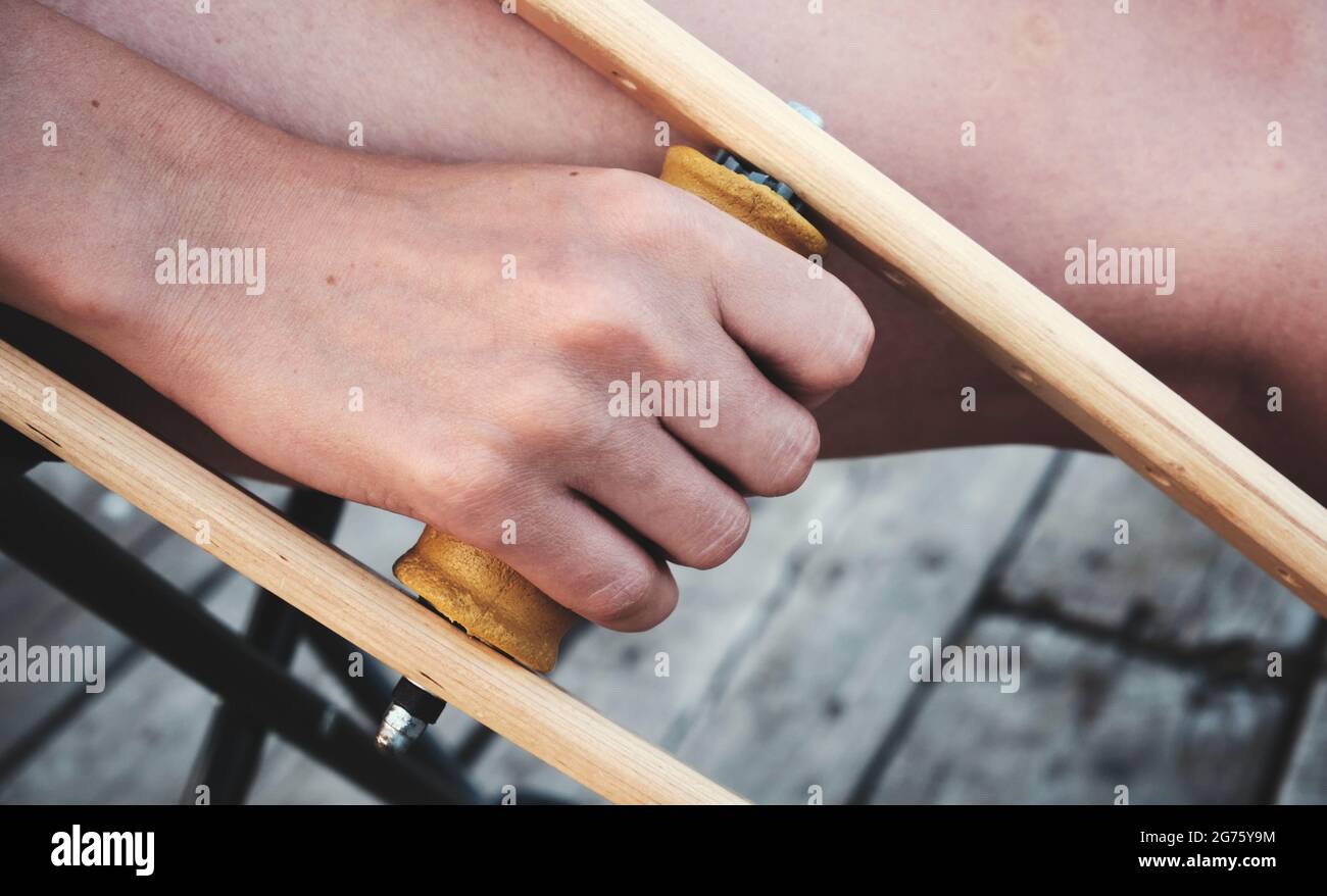 La mano della donna tiene un crutch. Lesioni alle gambe. Perdita di mobilità. Riabilitazione dopo una frattura. Foto Stock