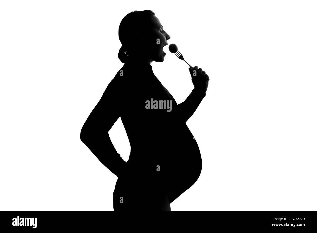 Giovane donna incinta che mangia la forchetta su uno sfondo bianco Foto Stock
