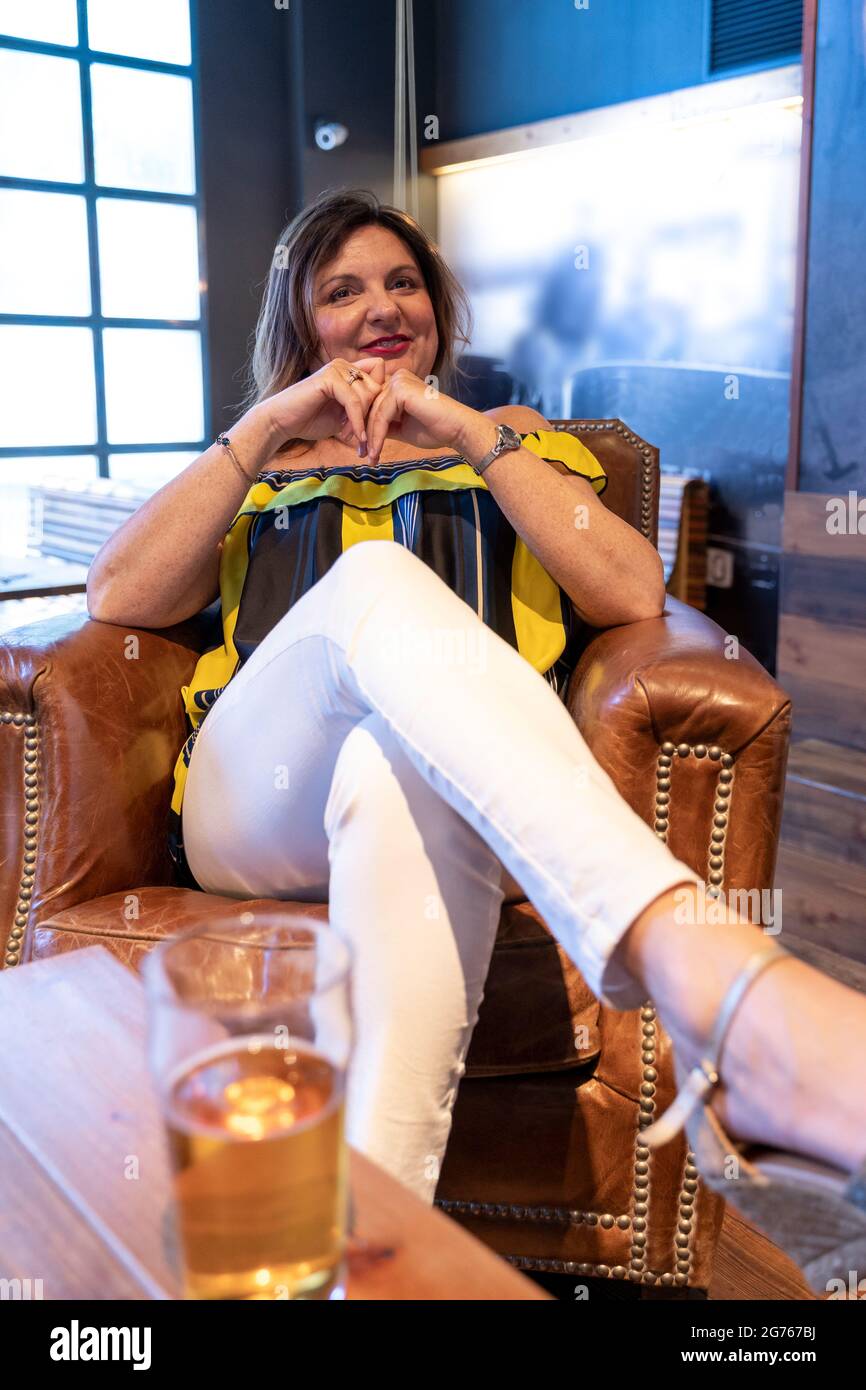 ritratto di bella donna che si rilassa su una sedia in pelle in un pub Foto Stock