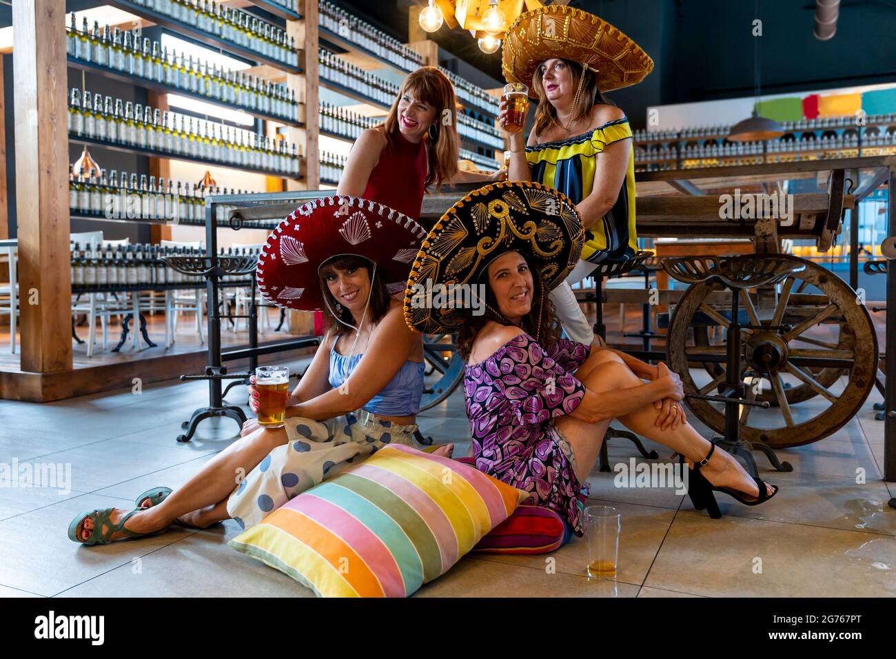 gruppo di donne attraenti che indossano sombreros messicani che hanno un buon tempo bevendo birra in un pub Foto Stock