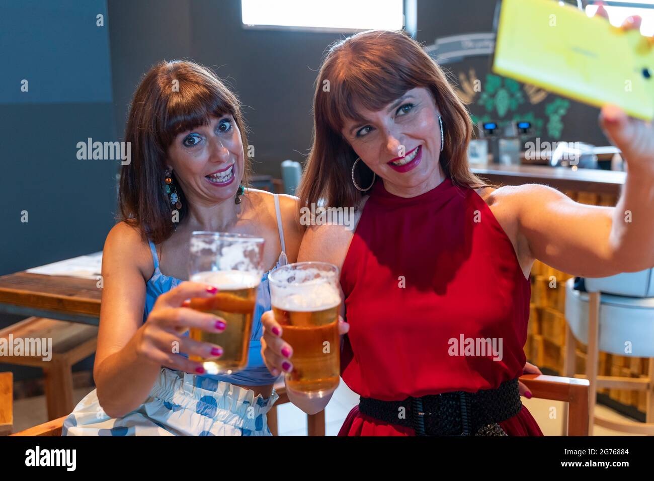 due amiche prendono un selfie mentre bevono birra in un pub Foto Stock