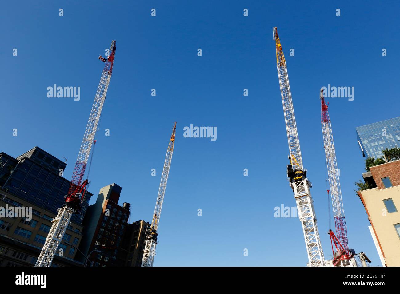 Quattro gru a torre luffanti contro un cielo azzurro soleggiato e senza nuvole in un cantiere nel quartiere Tribeca a Manhattan, New York, New York. Foto Stock